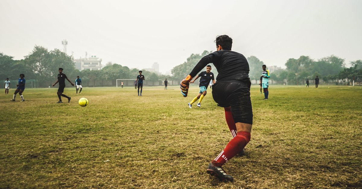 Energetic soccer game with players on a grassy field in India, showcasing teamwork and sportsmanship.
